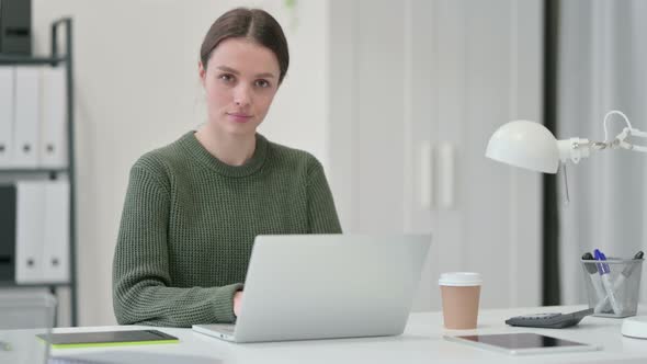 Young Woman with Laptop Shaking Head in Denial 