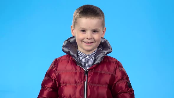 Boy Laughing and Looking at Camera, Posing Against Blue Background.