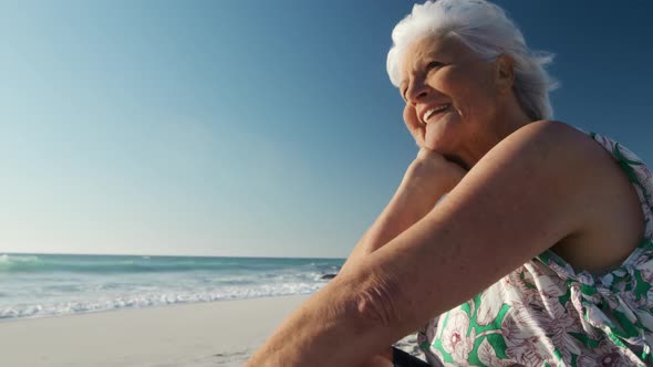 Senior woman sitting looking away at the beach