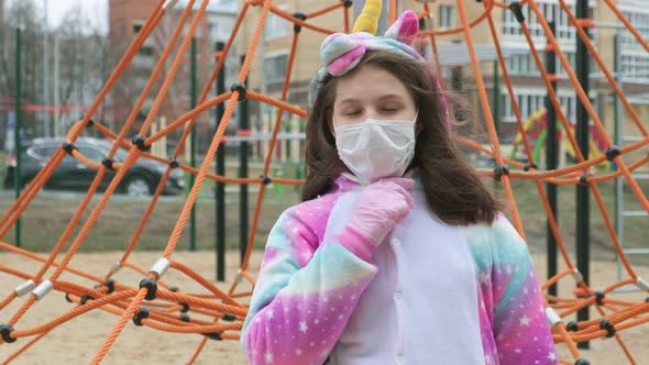 Young Girl in a Protective Mask at the Playground.