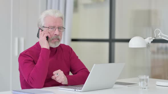 Old Man with Laptop Angry on Smartphone