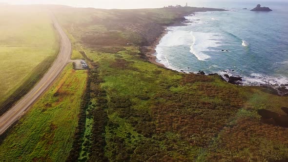 Aerial reveal of beach and highway at Peidras Blancas Lighthouse in California