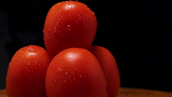 Close-up of ripe red tomatoes with condensation droplets spinning against a black background