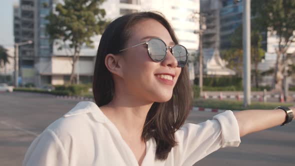 young Asia businesswoman hailing on road catching taxi and holding smart phone while.