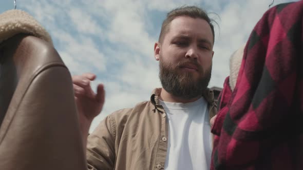 Man Looking at Second Hand Jackets at Garage Sale