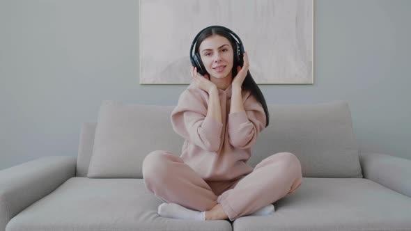 Millennial girl moving singing listening to music with wireless headphones.