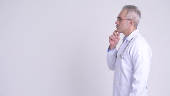 Profile View of Happy Persian Man Doctor Thinking Against White Background