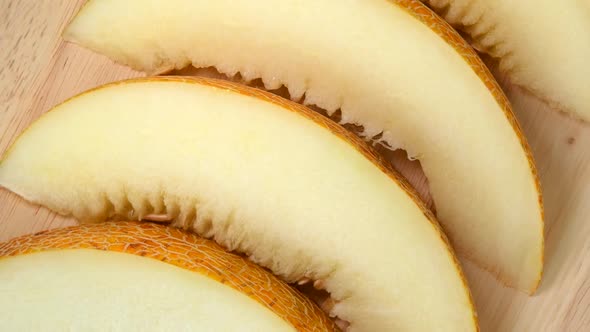 Slices of melon rotating top view on wooden background