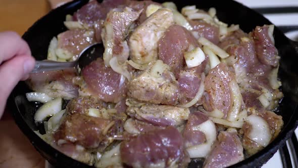 Female Hand Checks Readiness of Fried Meat with a Tablespoon