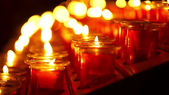 Red Candles with a flame close up view in a dark environment mood at a praying church