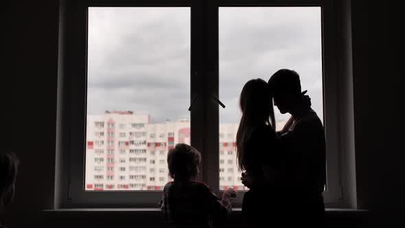 Silhouette of Lovers with Children on the Background of Windows From a New Apartment.