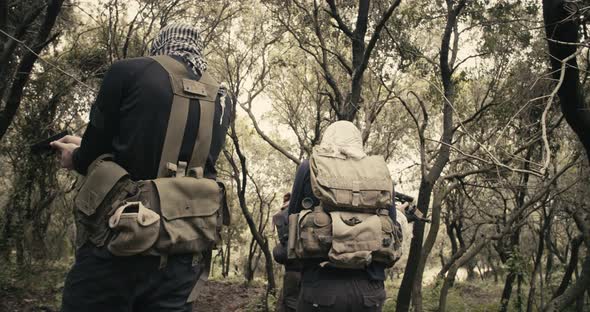 Squad of armed terrorists patrolling a forest area during combat