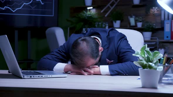 Male Business Person is Asleep in the Office at Night