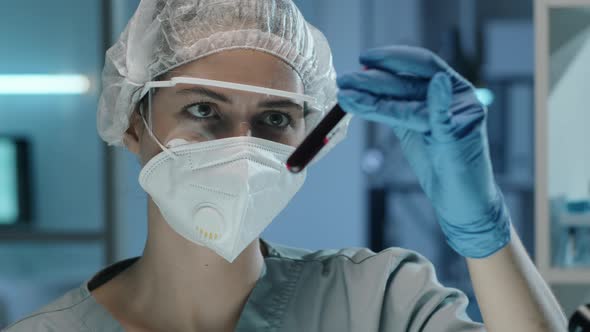 Female Lab Scientist Examining Blood in Test Tubes