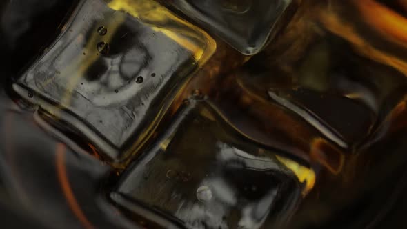 Pouring Whiskey, Cognac Into Glass with Ice Cubes. Pour of Alcohol Drink. Macro