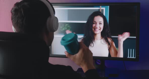 Rear View of a Young Man with Headphones Watching a Video Blog Indoors