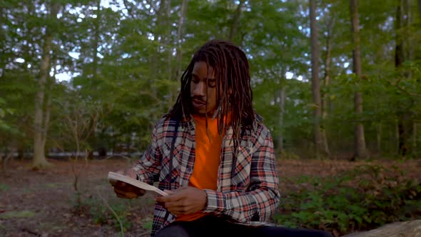 Gen Z Black Man Reads Book Outdoors in Public Park