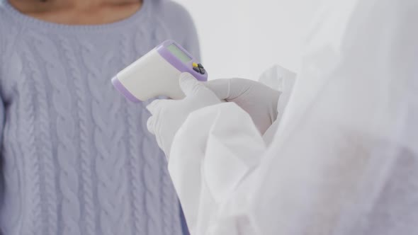 Woman wearing face mask getting her temperature measured