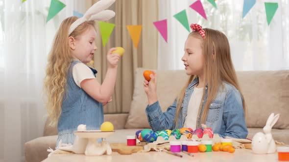 Little Girls with Rabbit Ears Play with Easter Eggs in Game of Who Will Break