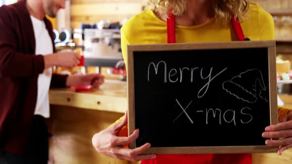 Portrait of waitress showing slate with merry x-mas sign