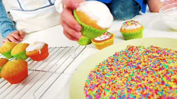 Man sticking confectionery on cupcake