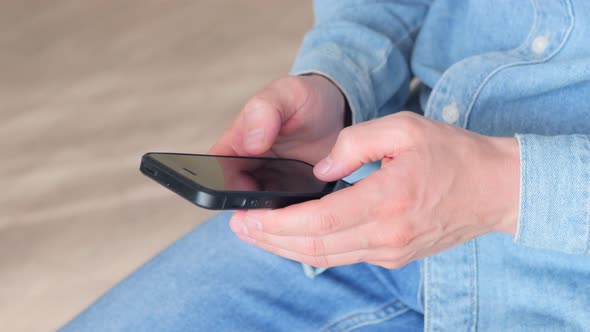 Side view. Hand of guy using smartphone typing message. Close-up of young male hand