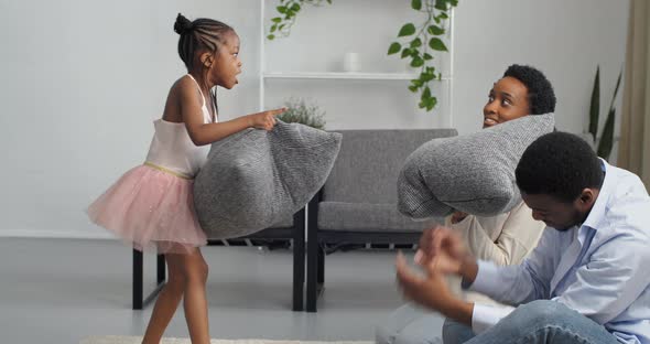 Afro American Family Mom Dad and Girl Child in Pink Dress Like Ballerina Fighting with Gray Pillows