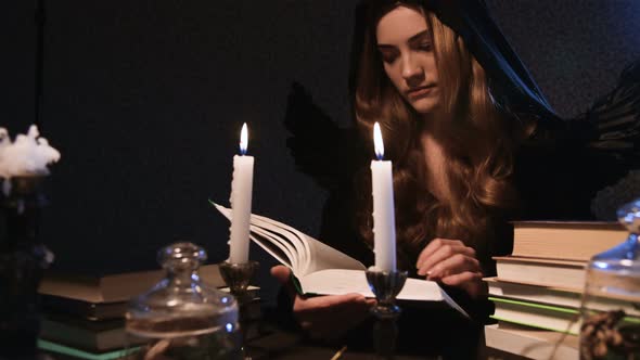 Portrait of a Young Attractive Woman in a Black Hoodie with a Hood and Wings with Long Hair Sits