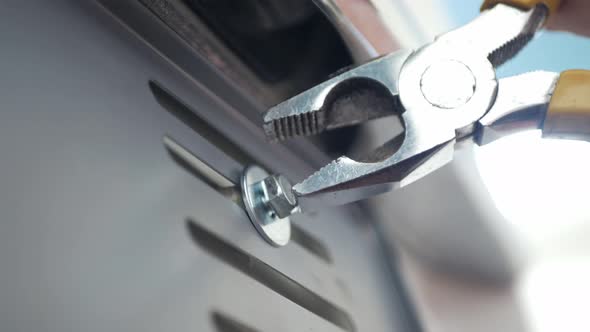 close up view mechanician use pliers tighten a bolt of the car's license plate on the car.install li