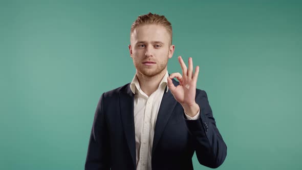 Man in Business Suit Showing Okay Sign Over Blue Background