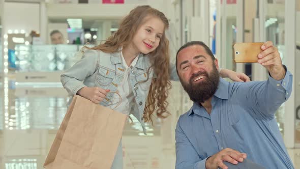 Adorable Little Girl Taking Selfies with Her Father at the Shopping Mall