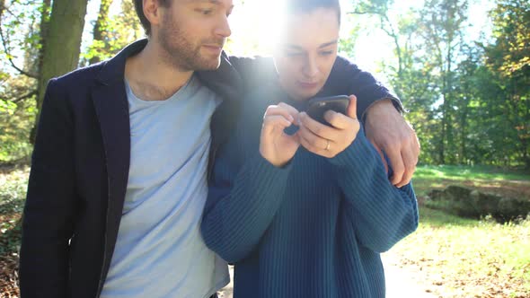 Couple looking at smartphone while strolling through park