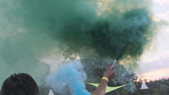 Man Having Fun with Colorful Smoke Flares Against the Sky. Slow Motion