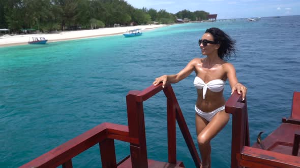 Awesome Skinny Brunette Girl in White Swimsuit Going Upstairs on Vintage Wooden Boat in the Ocean