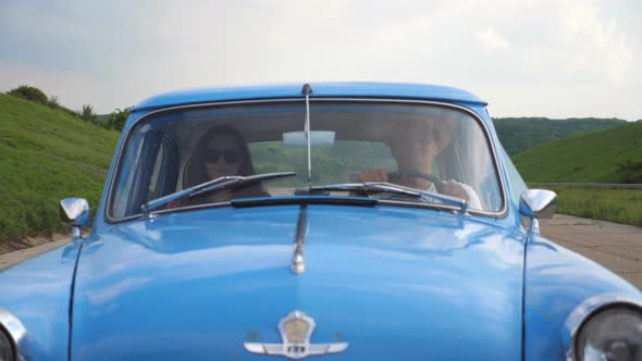Young Couple in Hats Riding in Vintage Car at Summer Travel