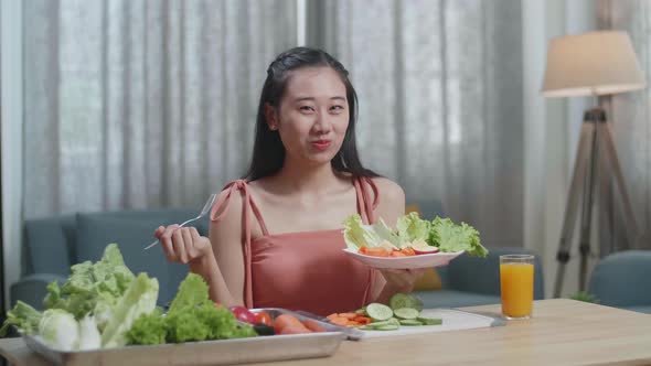 Smiling Asian Woman Enjoys Eating Healthy Food And Looking At Camera At Home