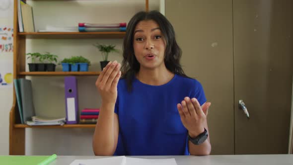 Mixed race female teacher sitting at desk having video call