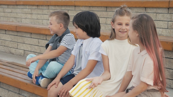 Two boys and two girls sitting on bench and talk.