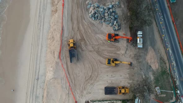 Drone footage of  large construction machinery used to repair beach sand dunes damaged by recent swe