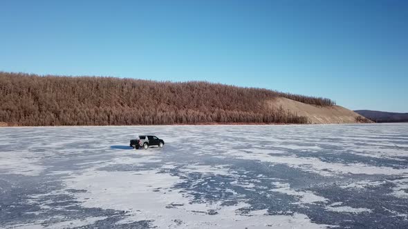 Drone Aerial View of Car in Winter Landscape and Hi Speed Driving Over the Frozen Lake