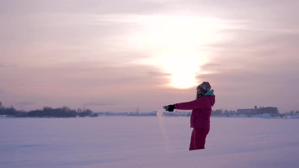 Girl is Splashing Out the Hot Boiled Water in the Cold Air on a Beautiful Winter Day at Sunset