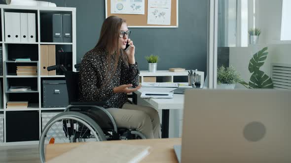 Disabled Office Worker Talking on Mobile Phone Sitting in Wheelchair Concentrated on Unpleasant