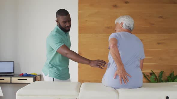 Video of african american male physiotherapist examining caucasian senior woman