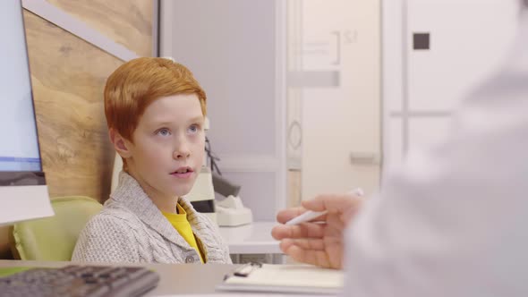 Little Redhead Boy Talking with Doctor in Clinic