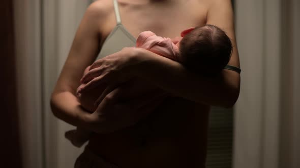 The camera zooms out from the newborn baby, which the mother is breastfeeding