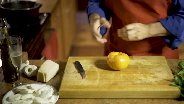 On a thick wood cutting board and chef takes a curved knife and cuts the core out of a yellow heirlo