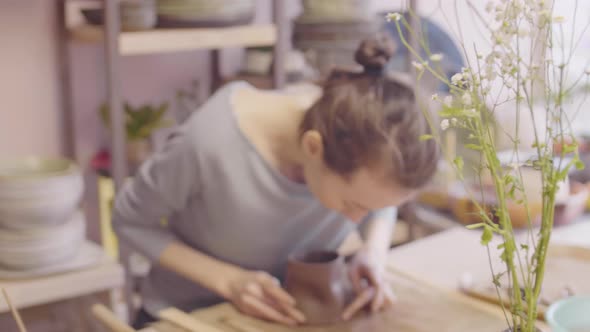 Young Woman Sculpting Cup in Ceramic Studio