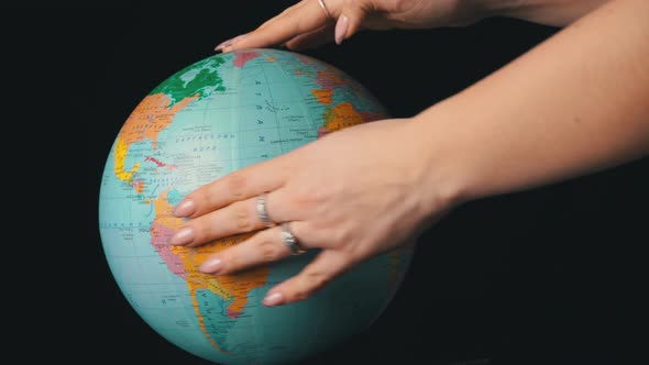 Geographical Globe is Twisted Around Its Axis By a Female Hand