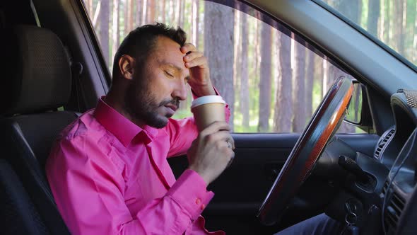 Frustrated Businessman Sits Behind the Wheel Drinks Coffee Thinks and is Sad