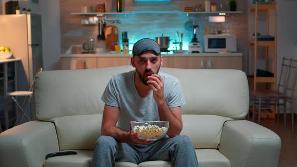 Concentrated Man with Sleep Eye Mask Sitting in Front of Television